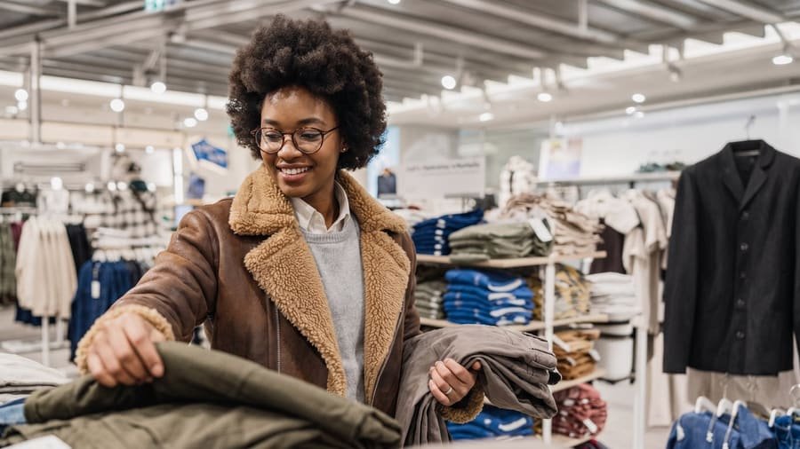 Woman browsing folded clothing on a table in a retail store