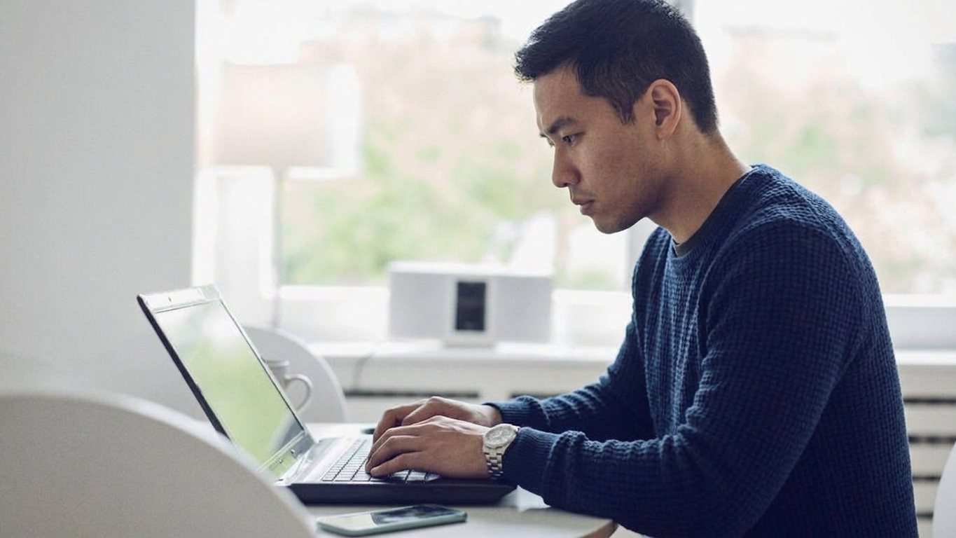 Man typing on a laptop at a home office desk